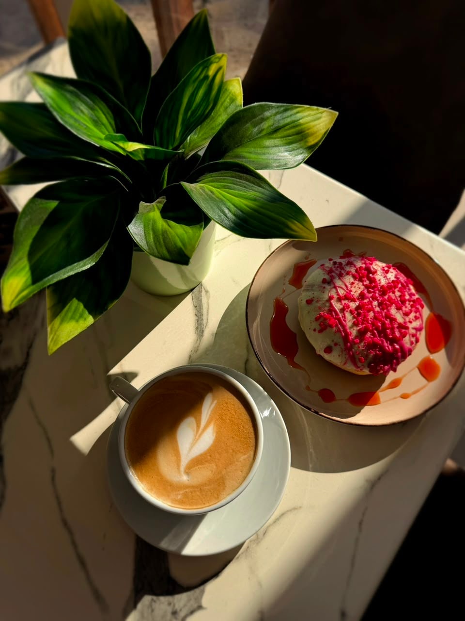Latte art coffee and donut on a marble table with Mouflon branding